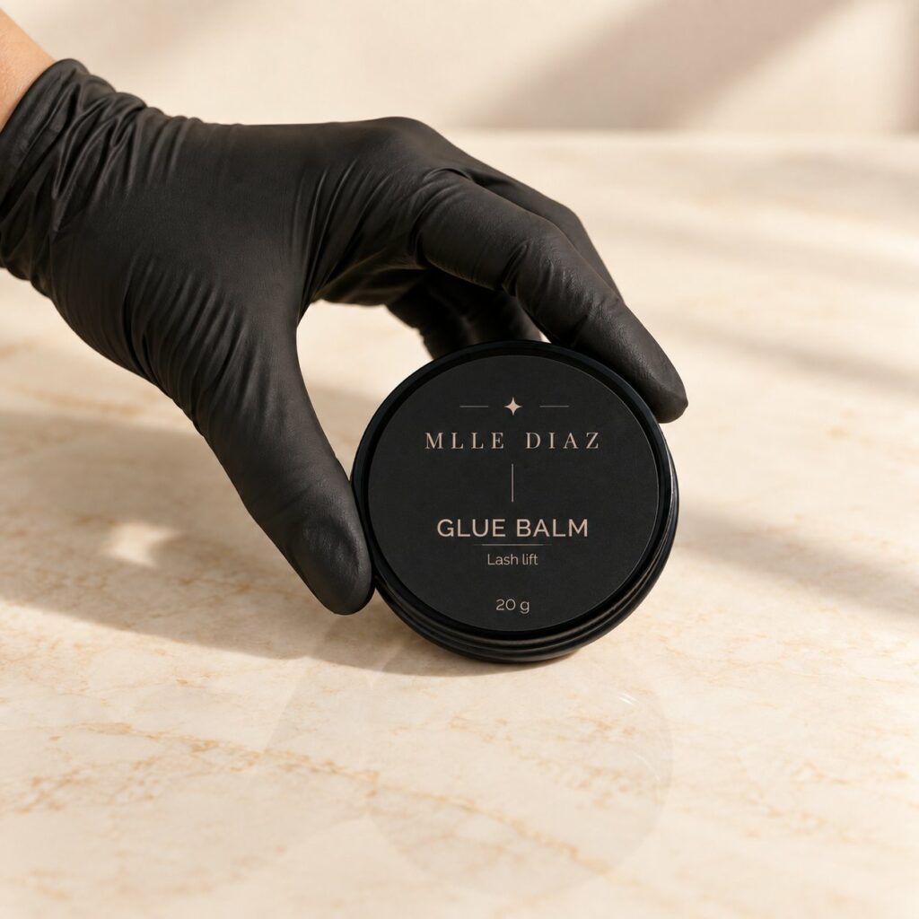 Main gantée tenant le pot de Glue balm Mlle Diaz