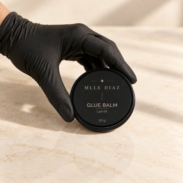 Main gantée tenant le pot de Glue balm Mlle Diaz